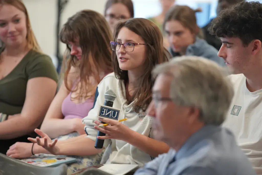 A student holding a microphone asks a question during a CECE event